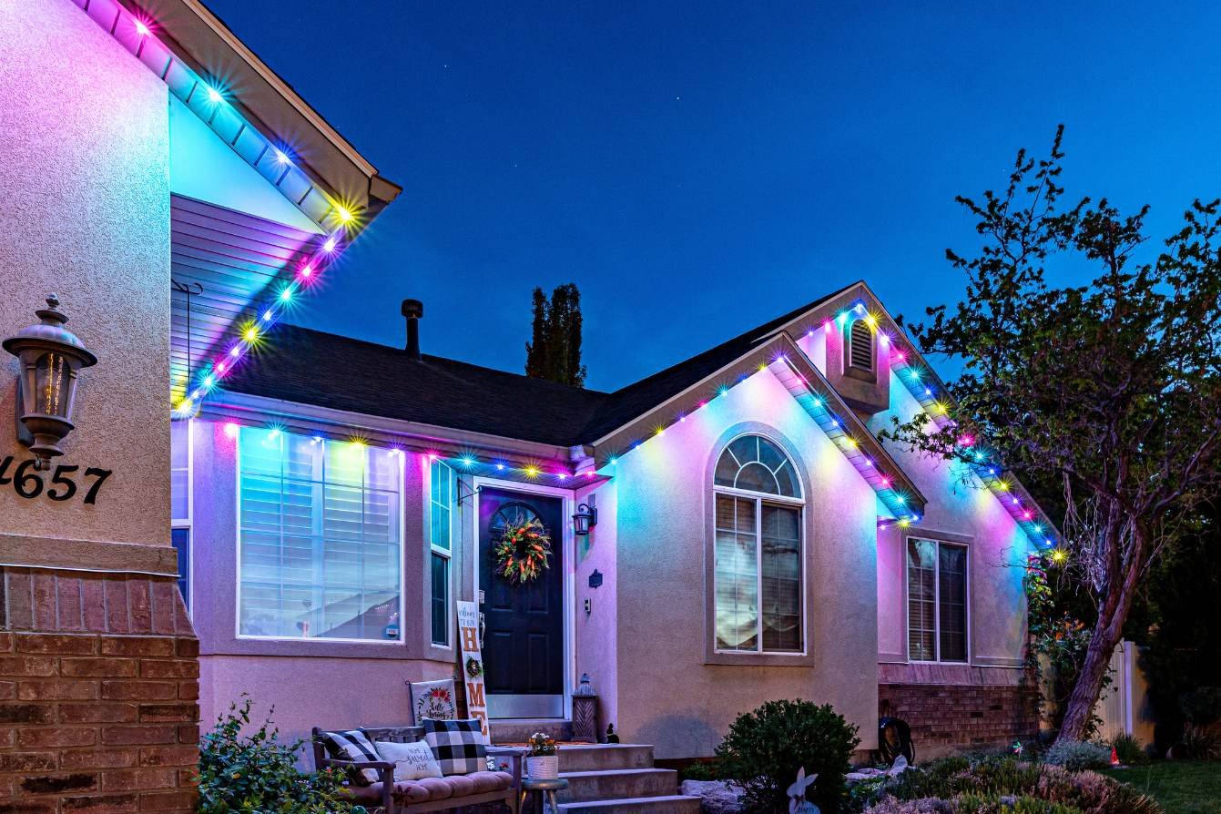 Home roofline outlined in red and green programmable holiday lights at night